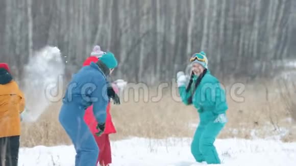 冬天一家人穿着五颜六色的羽绒服在森林里打雪球慢动作视频的预览图