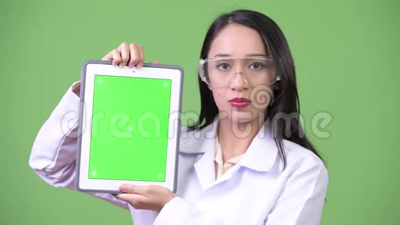 年轻漂亮的亚洲女医生戴着防护眼镜显示数字平板电脑视频的预览图