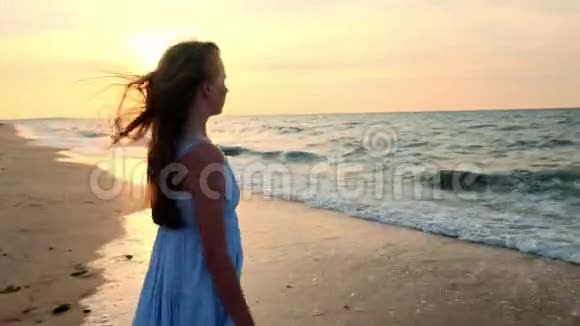 一个穿着白色连衣裙的女孩在日落时进入大海我对大海和海滩很满意体验自由去参加视频的预览图