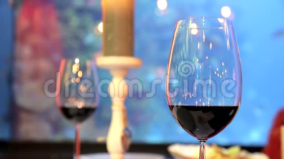 两杯红酒在背景中鱼漂浮在水族馆里视频的预览图