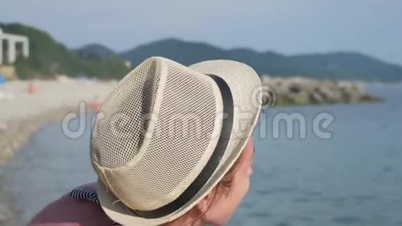 海滩上戴帽子的年轻漂亮女孩海上度假概念视频的预览图