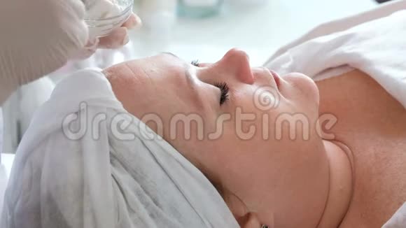 一个女人在美容院接受清洁皮肤的程序戴手套的美容师的手视频的预览图