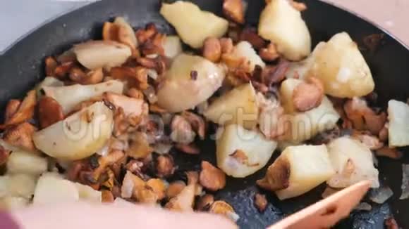 女人把食物放在盘子里用蘑菇和洋葱炒土豆特写的手视频的预览图
