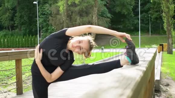 小女孩在公园的木桥上做伸展运动训练前热身慢动作视频的预览图