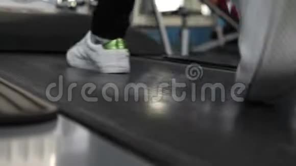 穿运动鞋的女孩的腿在跑步机上特写通过步行加强腿部肌肉在健身房散步心脏负荷女孩视频的预览图