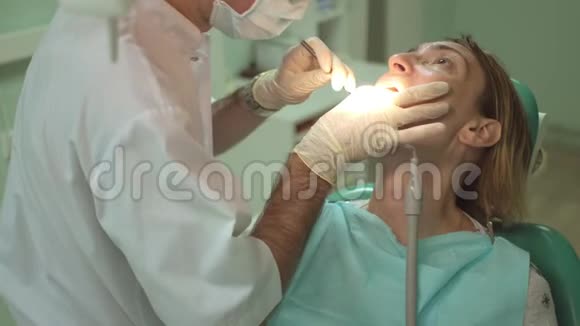 男牙科医生在牙科诊所用特殊设备治疗一颗漂亮的女牙视频的预览图