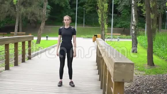 有魅力的女运动员在夏季在公园的木桥上做伸展运动健康视频的预览图
