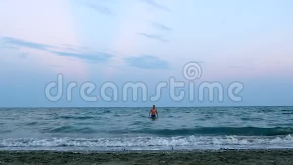 蓝色冶炼的年轻人从蓝色的海水中出来来到镜头海滩视频的预览图