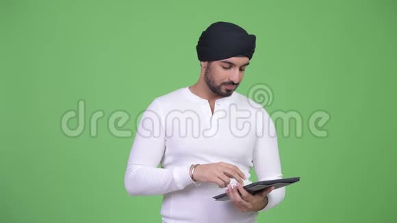 年轻的留胡子的印度男人使用数码平板电脑看上去很震惊视频的预览图
