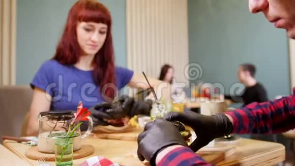 两个戴着黑色手套的人拿着黑色汉堡吃视频的预览图