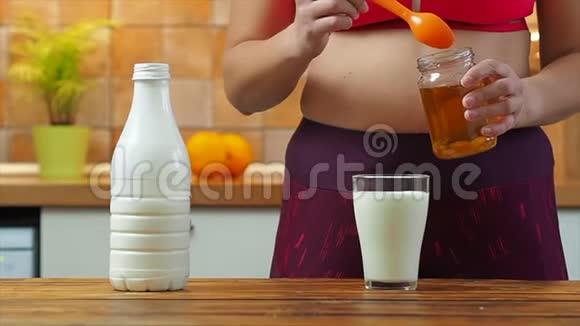 运动女孩把蜂蜜放进一杯杏仁牛奶里慢动作视频的预览图