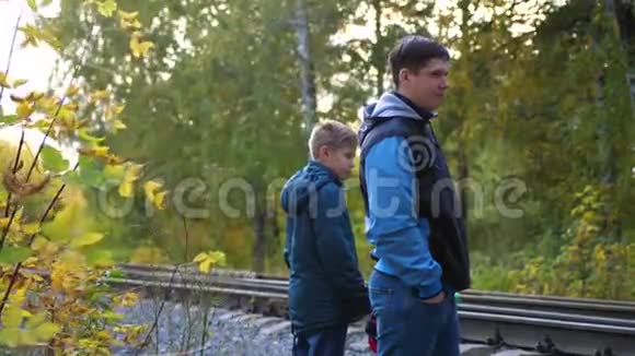 穿越铁路一家人站在铁路附近看着路过的机车秋天的公园风景如画视频的预览图