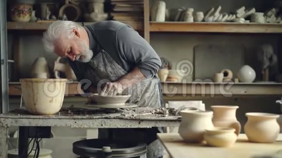 经验丰富的高级师傅正在小作坊制作陶轮上的低粘土碗陶瓷夹具手工制作视频的预览图