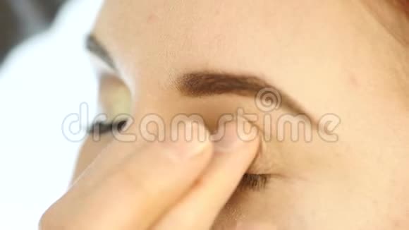 特写化妆师的手用手指把眼影涂在女人眼睛上视频的预览图