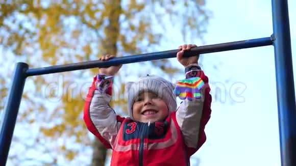 在新鲜空气中锻炼一个小男孩在水平杆上做运动秋季公园视频的预览图