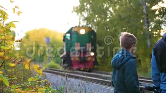 穿越铁路一家人站在铁路附近看着路过的机车秋天的公园风景如画视频的预览图