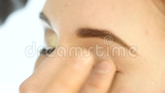 特写化妆师的手用手指把眼影涂在女人眼睛上视频的预览图