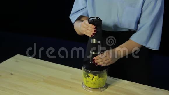 女人在黑色背景下用搅拌器烹制猕猴桃和芒果视频的预览图