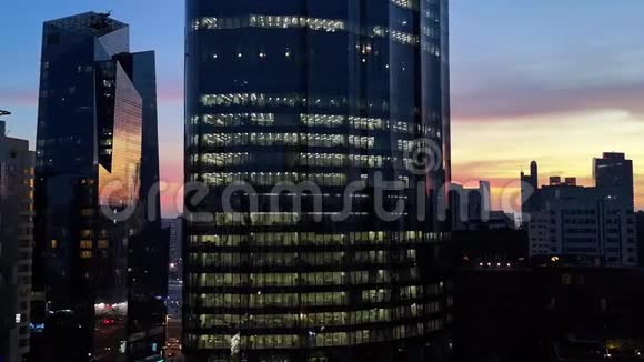 在多云的日落中闪烁的摩天大楼窗户现代办公室和摩天大楼的景色视频的预览图