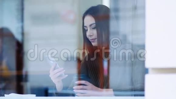 一位年轻貌美的美女坐在一家咖啡馆的窗户旁在网上冲浪视频的预览图