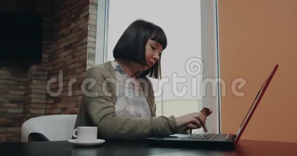一位留着短发的年轻女士用卡片从笔记本电脑上订购一些东西视频的预览图