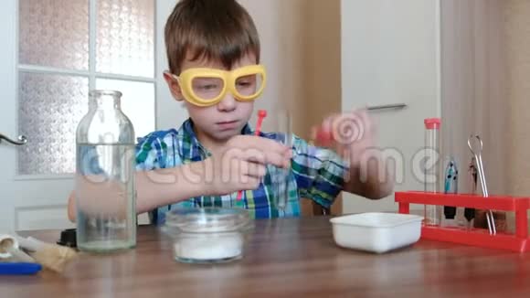 家庭化学实验男孩用铲子把粉末倒进瓶子里视频的预览图