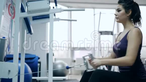 运动女孩深色头发在健身房的动力模拟器上做漂亮的身体视频的预览图
