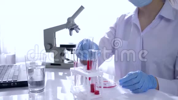 研究血液女性戴橡胶手套和眼镜在现代实验室使用试管和试剂视频的预览图