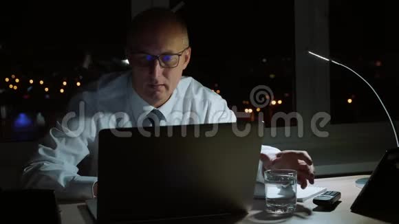 行政商人在黑暗的办公室里用玻璃喝水视频的预览图