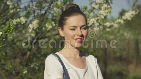 微笑美丽的女人靠近开花的树视频的预览图