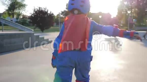 体育活动穿着超级英雄服装的无畏的孩子骑在滚轮上在滑板公园挥舞双手视频的预览图