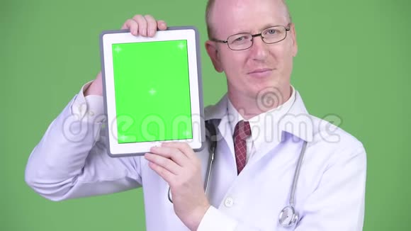 一位成熟的秃头医生正在用数码平板电脑视频的预览图