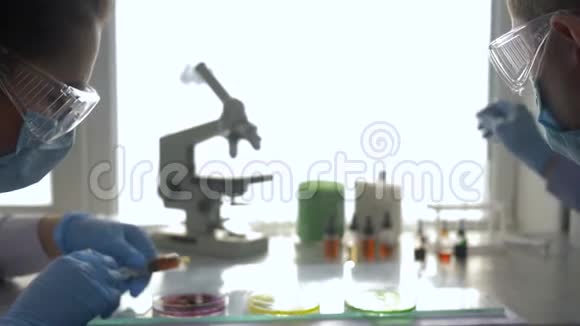 带注射器和试剂的口罩和眼镜的实验室助理进行化学实验视频的预览图