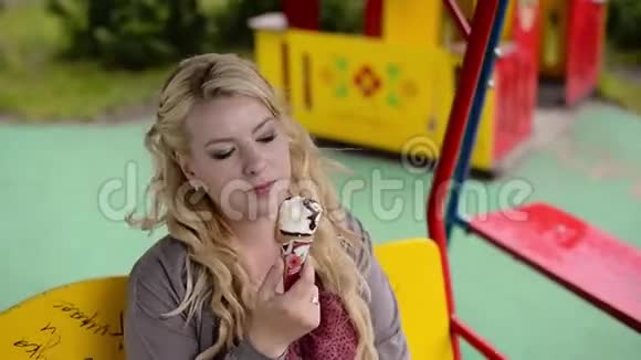 年轻可爱的金发女孩在秋千上吃冰淇淋视频的预览图