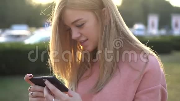 年轻女孩看着智能手机屏幕微笑视频的预览图