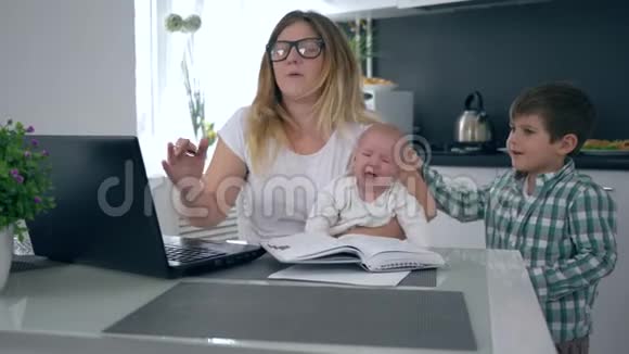 妈妈怀里抱着哭泣的婴儿尖叫着儿子儿子在家里干扰工作视频的预览图