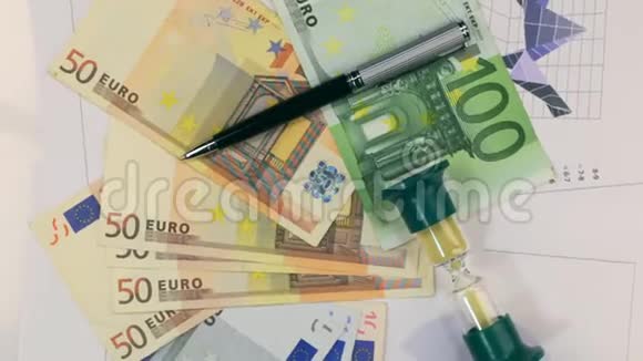 旋转沙漏和笔躺在欧元上上景视频的预览图