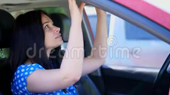 美丽的黑发女人坐在车里照着镜子把发型理直气壮地化妆视频的预览图