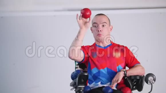 坐轮椅的残疾人在空中扔一个红色的小球肖像视频的预览图