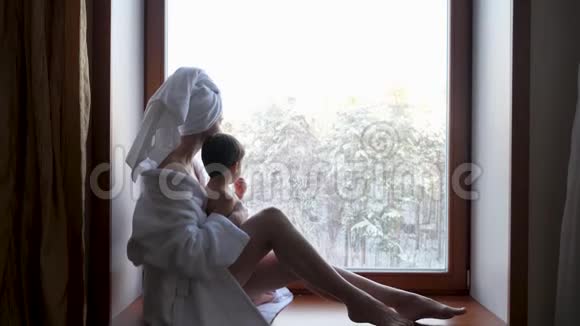 妈妈和儿子穿着浴袍坐在窗户上视频的预览图