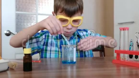 家庭化学实验男孩用玻璃棒混合烧杯中的蓝色液体和粉末视频的预览图