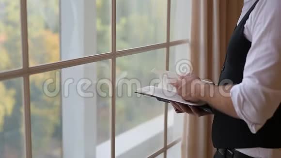 一个年轻人站在窗边翻书视频的预览图