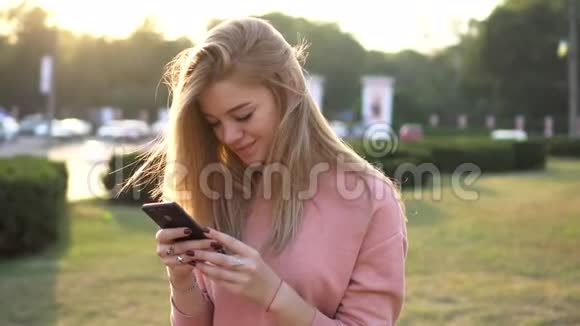 年轻女孩看着智能手机屏幕微笑视频的预览图
