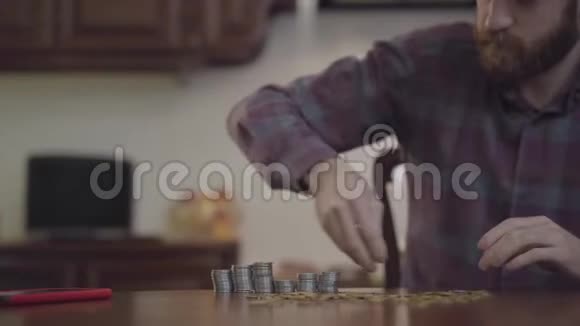 坐在厨房里数钱的桌子旁的留胡子男人的画像穿着格子衬衫的胡子银装素裹视频的预览图