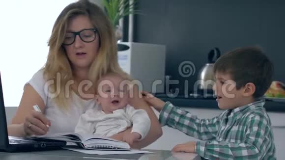 母亲头痛厌倦了工作和孩子女人牵着头看镜头视频的预览图