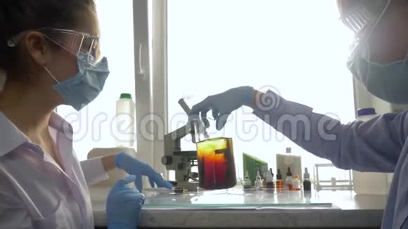 科学家在实验实验室中将试剂放入大玻璃中的化学溶液中视频的预览图