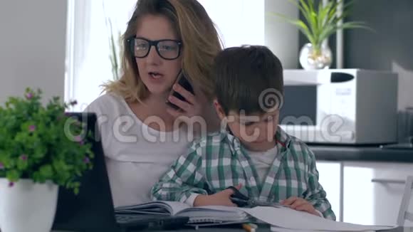 女人把教养孩子和工作结合起来母亲用手机用电脑说话而儿子在她身边玩耍视频的预览图