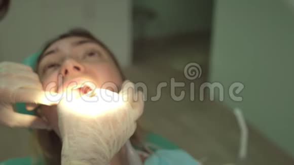 在牙科椅上用年轻的牙医检查和特殊照明为美丽的妇女做特写视频的预览图