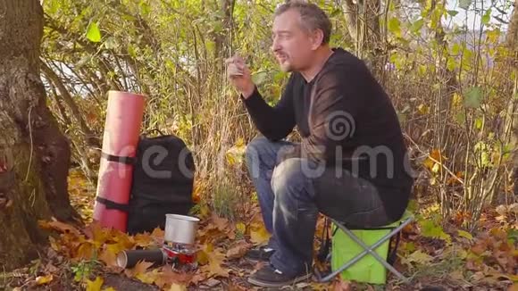 在秋天的森林里烧煤气游客试着从锅里取出食物视频的预览图