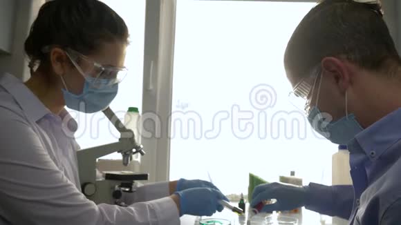 年轻的科学家在现代实验室进行化学液体的合成和显微镜检查视频的预览图